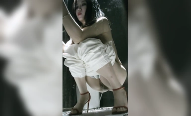 Bức ảnh toàn cảnh chân thực về một người đẹp có làn da trắng nõn trong bộ đồ một mảnh trong nhà vệ sinh nữ của nhà hàng, với búi tóc bụ bẫm, âm hộ trắng nõn và bộ ngực khủng