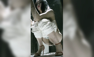 Bức ảnh toàn cảnh chân thực về một người đẹp có làn da trắng nõn trong bộ đồ một mảnh trong nhà vệ sinh nữ của nhà hàng, với búi tóc bụ bẫm, âm hộ trắng nõn và bộ ngực khủng